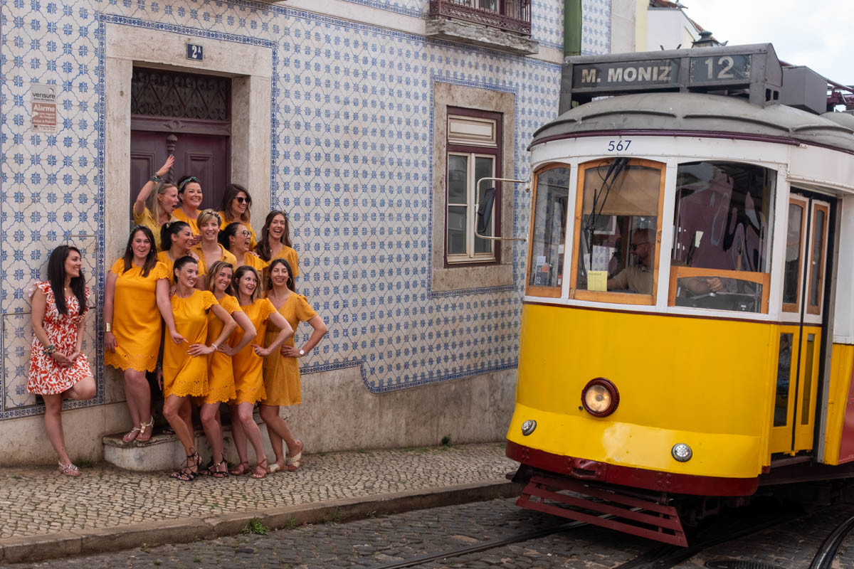 Séance EVJF à Lisbonne, groupe de femmes en robes jaunes devant un tramway typique