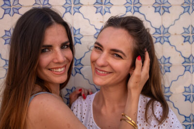 Portrait de deux amies souriantes devant un mur d'azulejos à Lisbonne