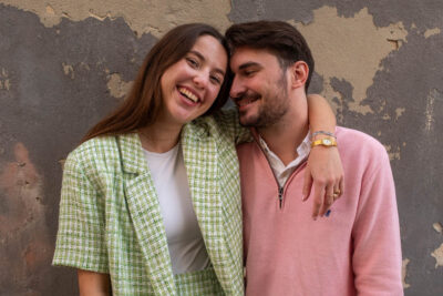 Smiling couple photoshoot against a weathered wall in Alfama, Lisbon