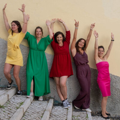 Sessão de despedida de solteira em Lisboa, grupo de mulheres de vestido colorido numa escadaria em Alfama