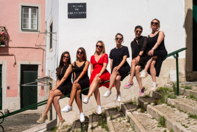 Bachelorette photoshoot in Lisbon, group of women sitting on a railing at Calçada de São Vicente