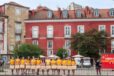 Séance EVJF à Lisbonne, longue rangée d'amies en robes jaunes devant une façade rouge