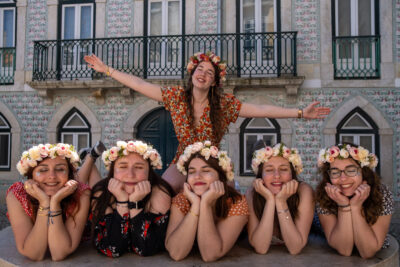 Séance EVJF à Lisbonne, groupe d'amies en couronnes de fleurs devant une façade avec balcon