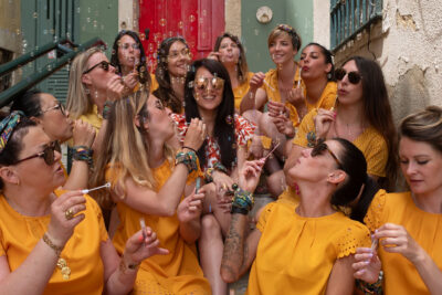 Sessão de despedida de solteira em Lisboa, grupo de mulheres de vestido mostarda a soprar bolhas de sabão