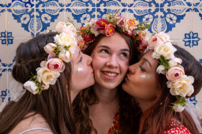 Portrait de trois amies en couronnes de fleurs s'embrassant sur les joues à Lisbonne